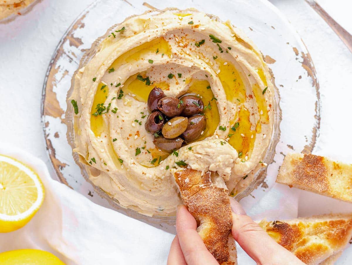 hummus con olive e una mano