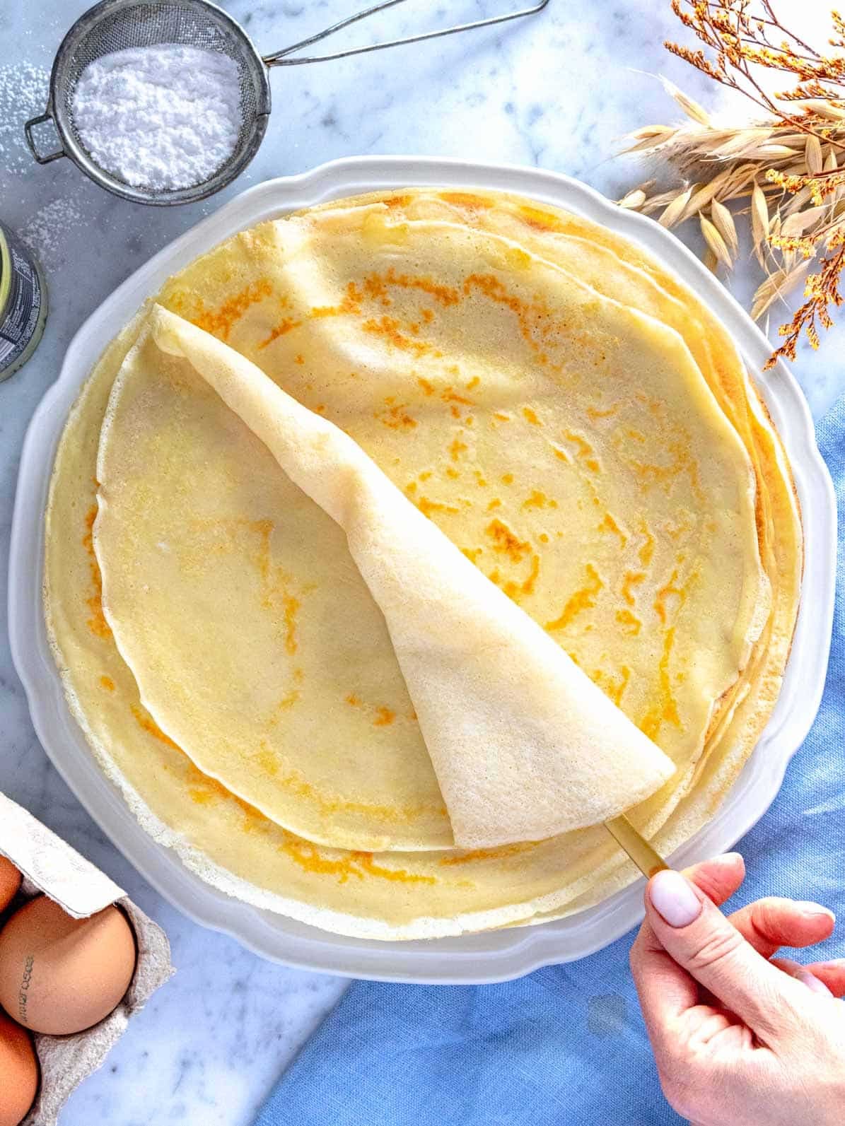 Crepes sul piatto con una mano femminile.